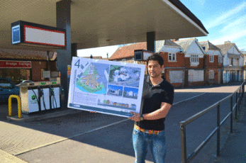 Alex Dean of Bridge Homes with plans for the Bridge Garage site, in front of the filling station forecourt, with the listed buildings in the background